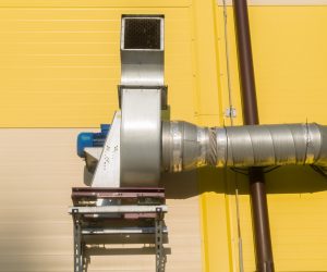 Dirty air extraction system. Equipment installed outside the building for exhaust and air filtration. Electric motor with an air pipe on the wall of the building. Selective focus.